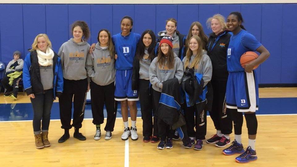 The touring Ramblers junior girls' team pose on court with two Duke University players in blue after a training session.