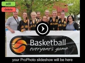 A Ramblers junior girls' team wearing medals pose behind a 'Basketball, everyone's game' banner with two coaches.