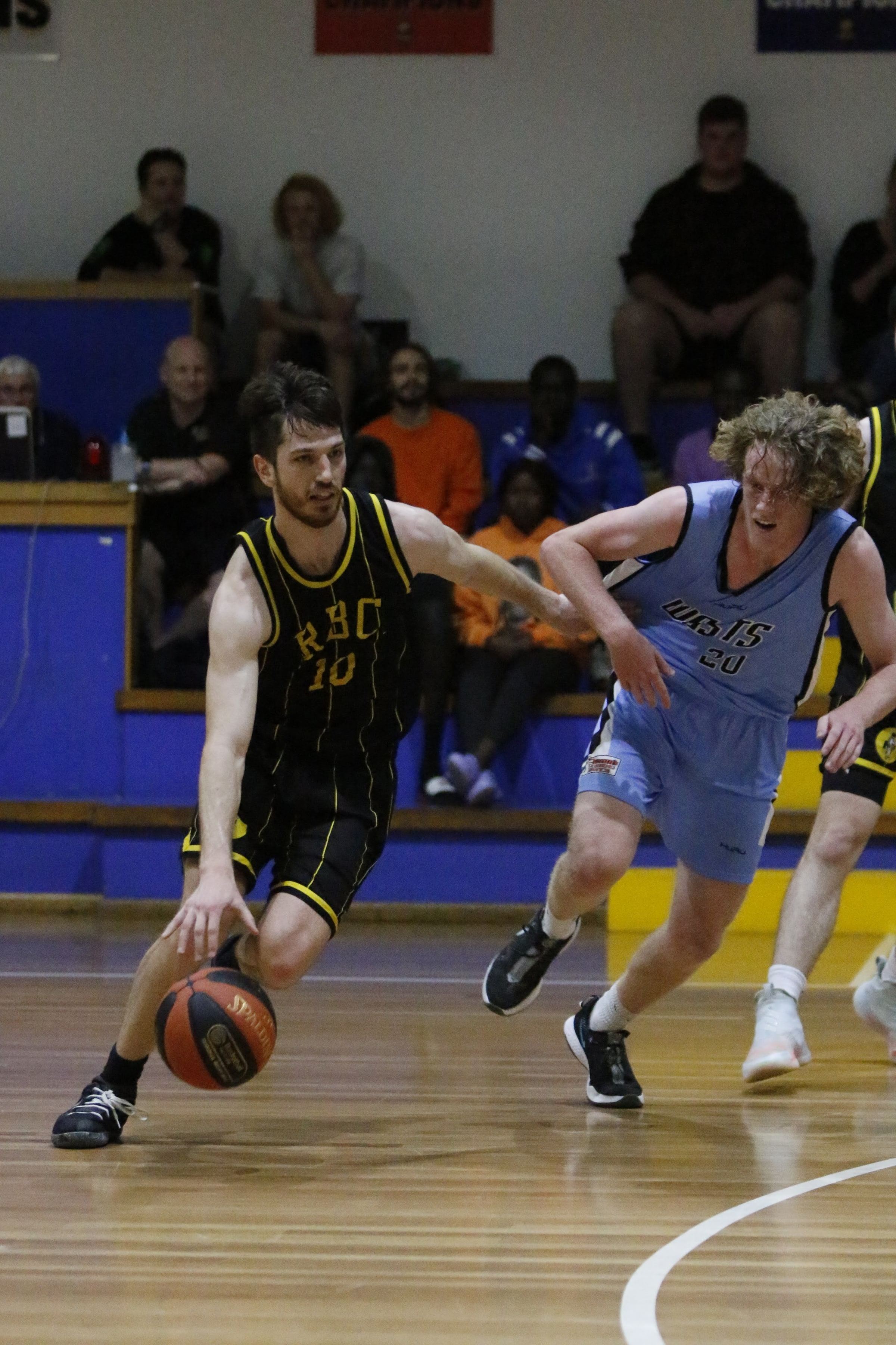 A Ramblers senior player in a black and gold RBC jersey drives past a defender during a trial game.