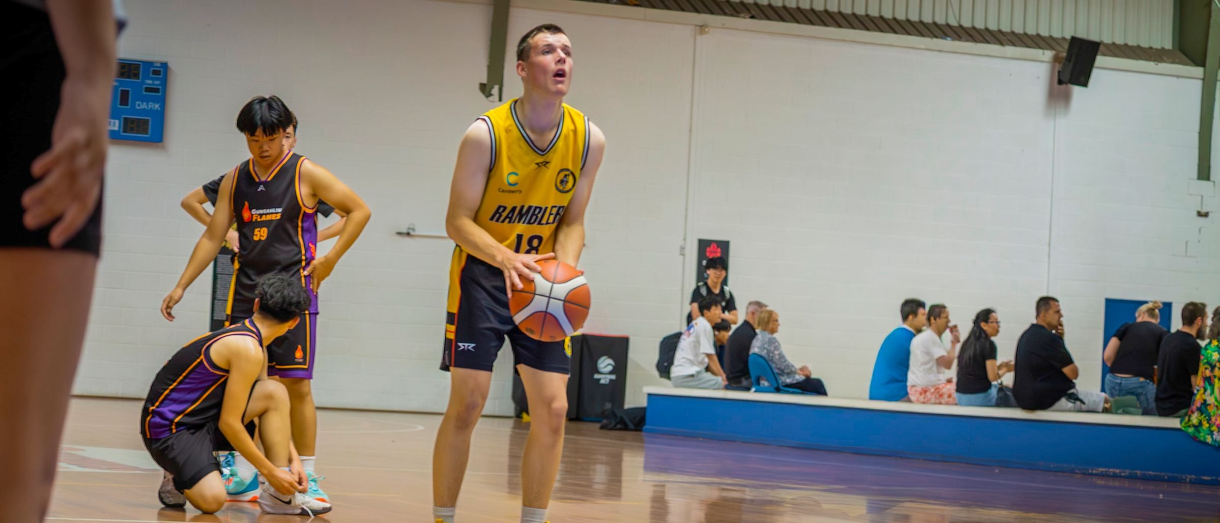 A Ramblers player prepares to shoot a free throw while families watch from the sideline